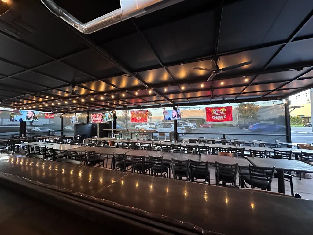 Covered patio with Chiefs decor, tables, chairs, and multiple sports TVs.