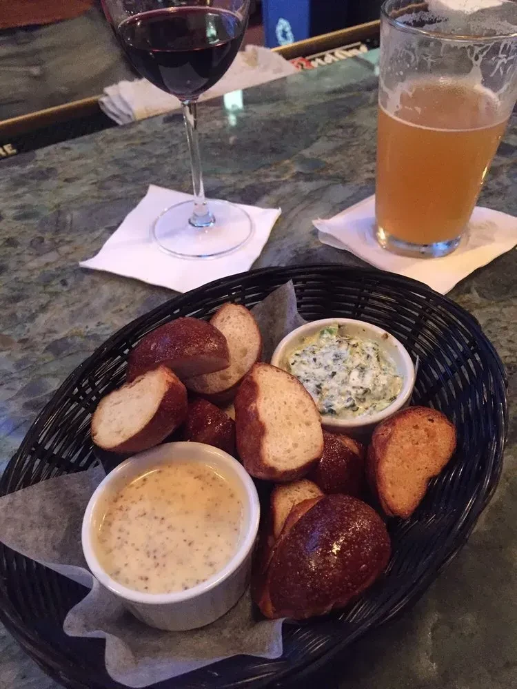 Basket of pretzel bites, two dips, red wine, and amber beer.