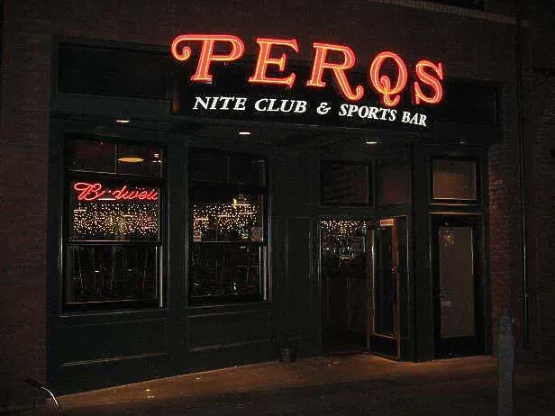 Perqs Nite Club & Sports Bar's neon-lit exterior at night.