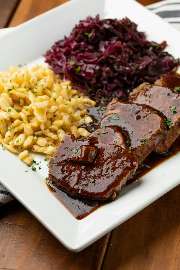 Sliced roasted meat with gravy, spaetzle, and braised red cabbage.