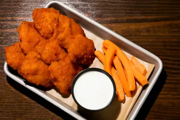 A metal tray with bon boneless buffalo chicken, dip, and carrot sticks.