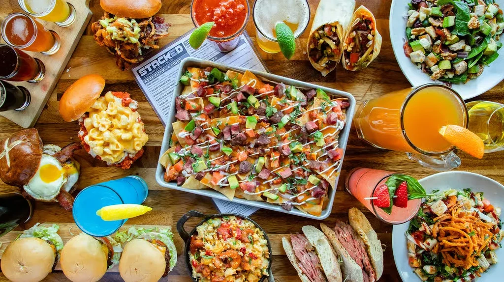 Overhead view of a wooden table laden with diverse food and drinks.