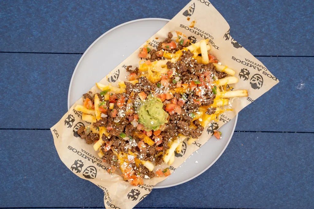 Loaded french fries with ground meat, melted cheese, vegetables, and guacamole.
