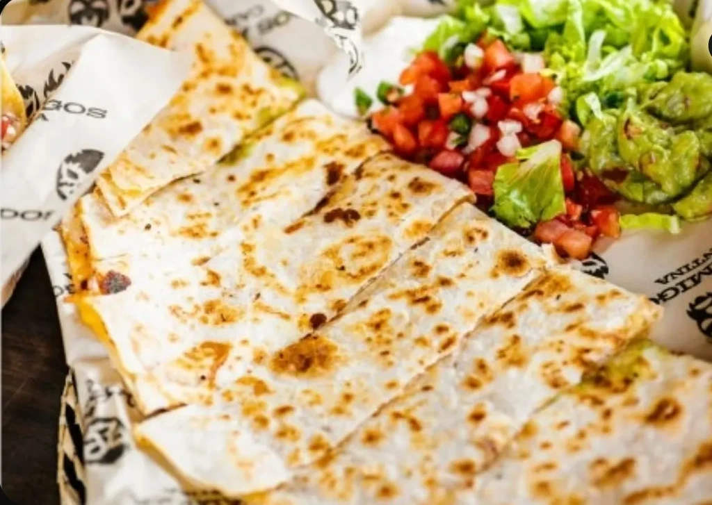 Golden-brown quesadilla triangles with guacamole, pico de gallo, and shredded lettuce.