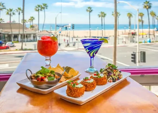 Food and drinks on a table with a sunny beach view.
