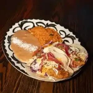 Plate with three tacos, refried beans, and Mexican rice.