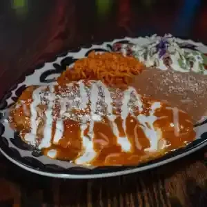 A plate of Mexican enchiladas with rice, beans, and coleslaw.