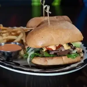 Two sliders on a cow-print plate with fries and dipping sauce.
