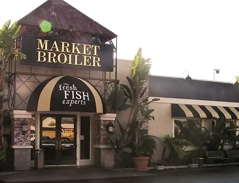 MARKET BROILER restaurant exterior with prominent sign, striped awnings, and plants.