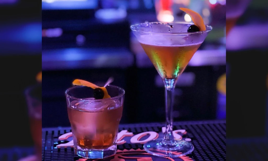 Amber cocktails in rocks and martini glasses on a bar mat.