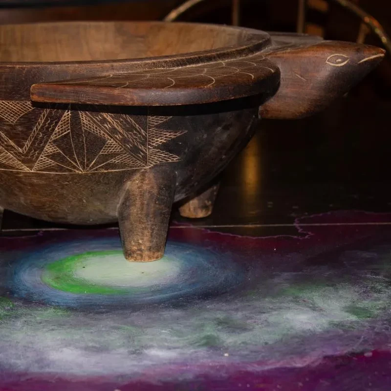 Intricately carved wooden turtle vessel on a vibrant galaxy surface.