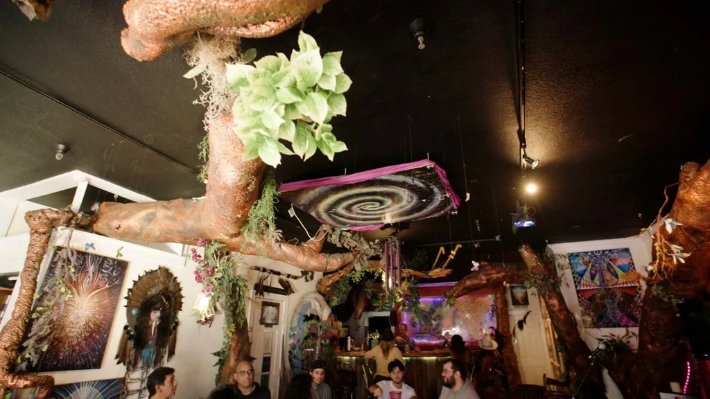 Fantasy bar interior with sculptural trees, galaxy art, and patrons.