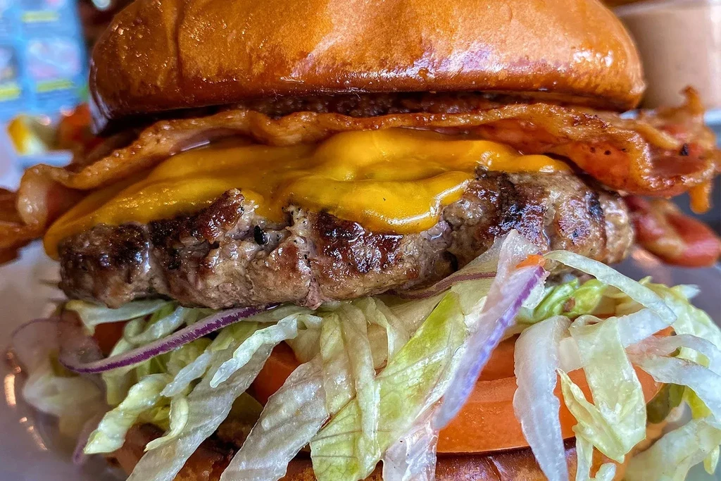 Juicy beef burger with melted cheese, crispy bacon, and fresh vegetables.