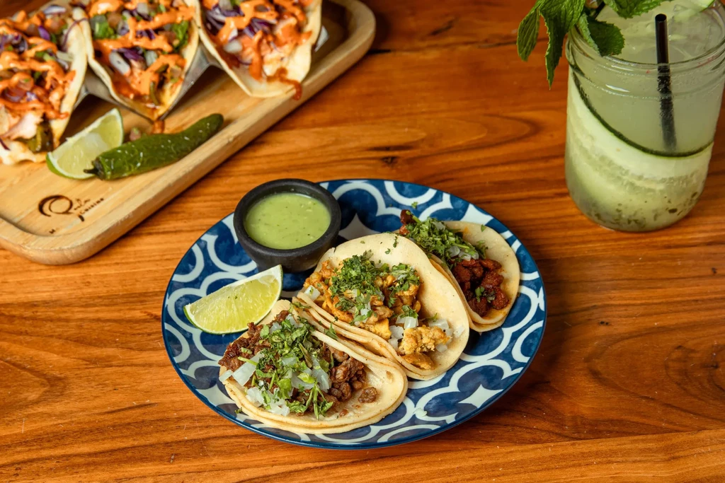 Mexican-style food spread with tacos, sauce, and a refreshing green drink.
