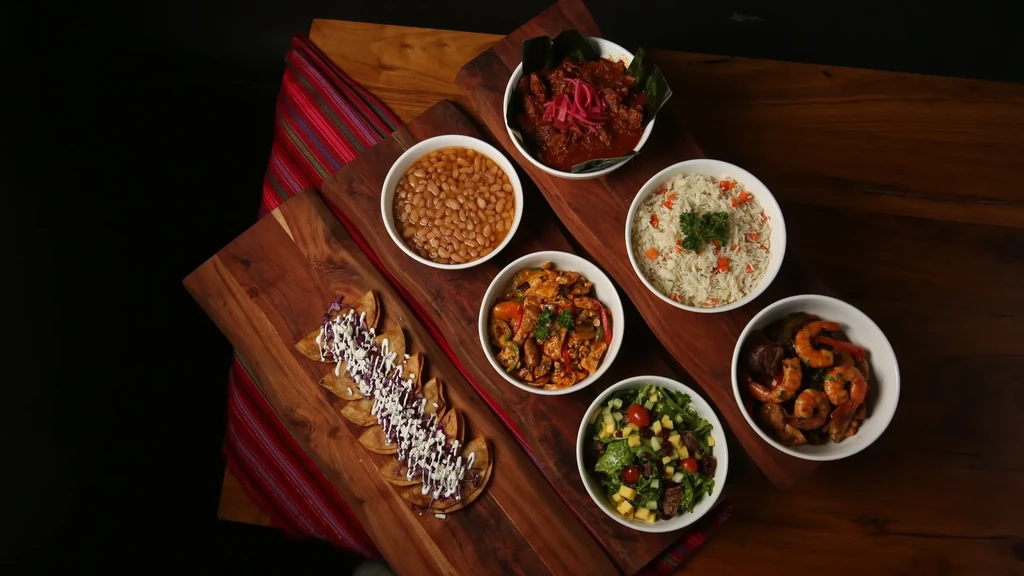 Spread of Latin American dishes: tacos, stew, rice, shrimp, salad.