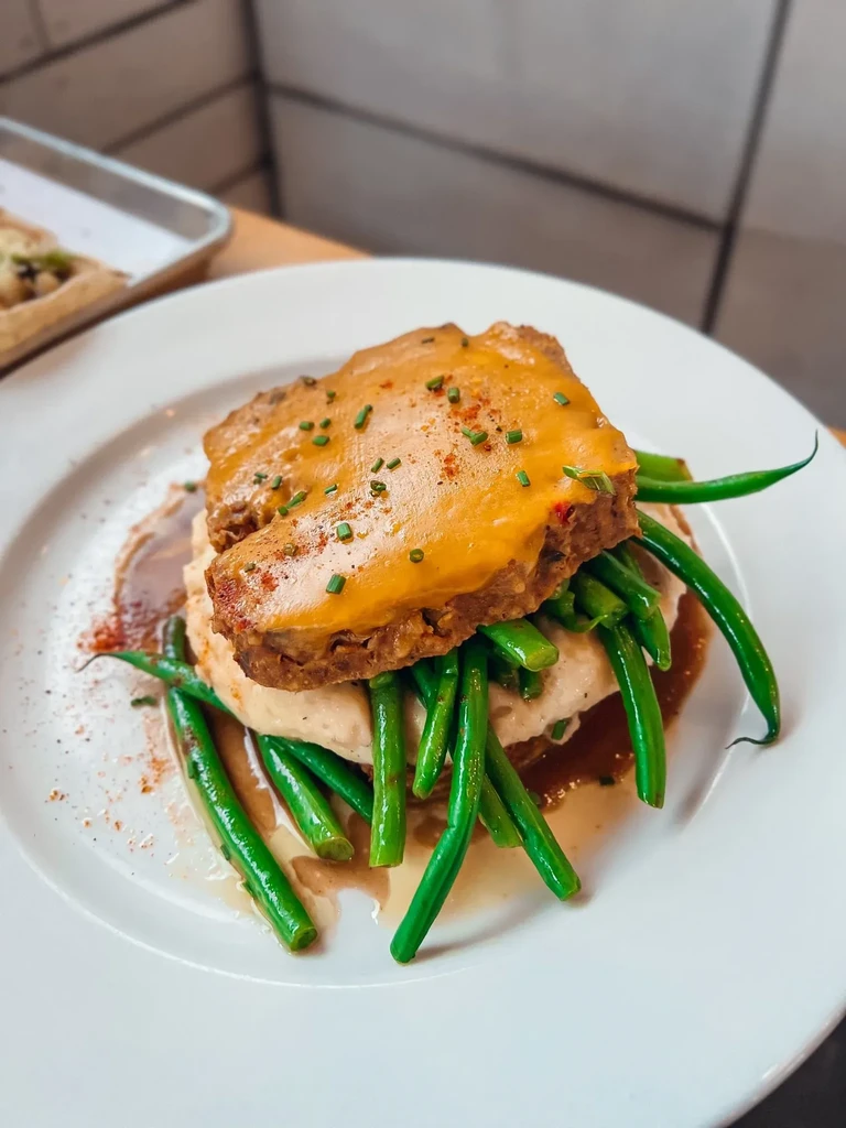 Meatloaf with yellow sauce, chives, mashed potatoes, green beans, gravy.