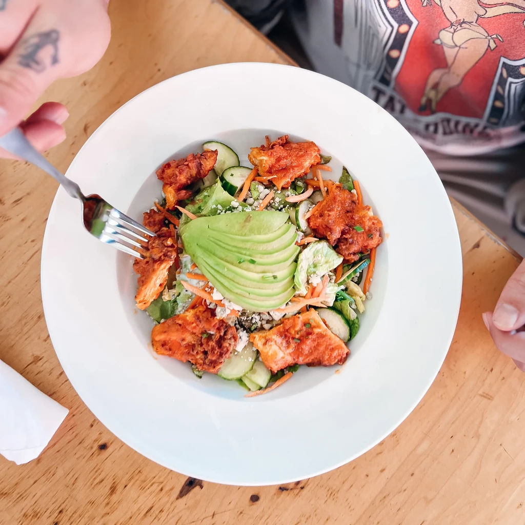 Top-down view of a colorful buffalo chicken and avocado salad.