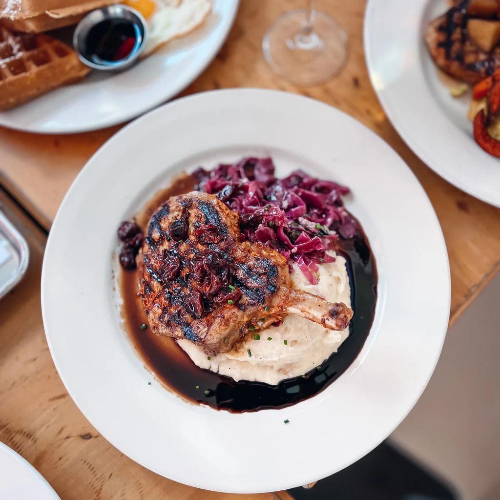 Grilled pork chop on mashed potatoes with braised cabbage and berries.