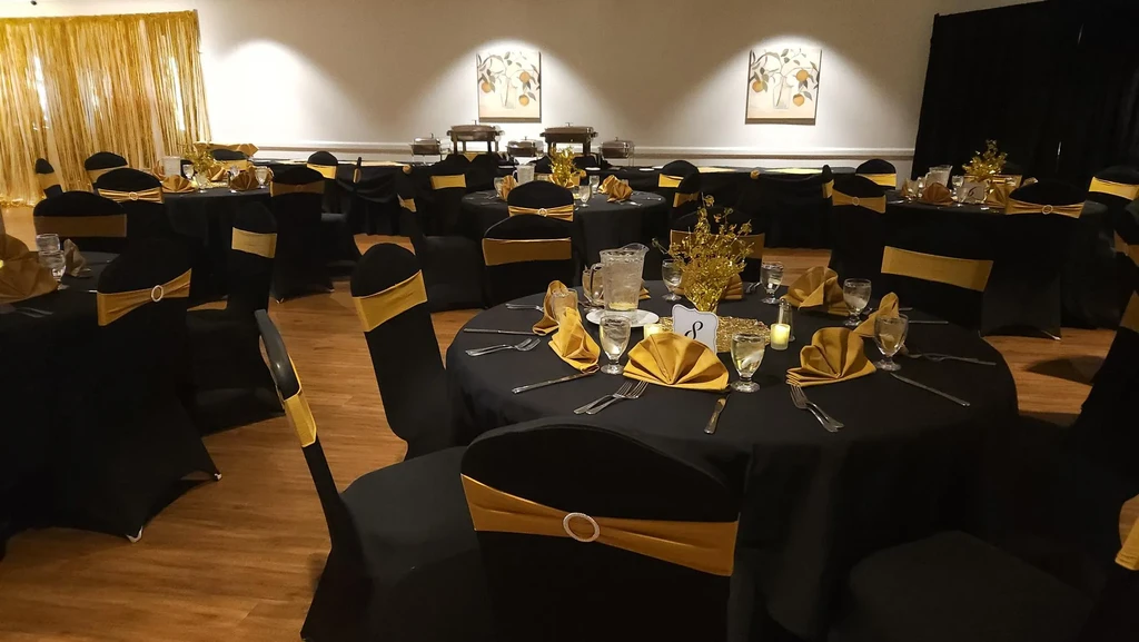 Formal event space with black tables, gold chairs, and buffet setup.