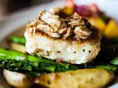 Seared white fish topped with crab, asparagus, and roasted potatoes.