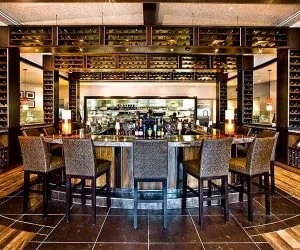 Upscale semi-circular bar with extensive wine racks and open kitchen.