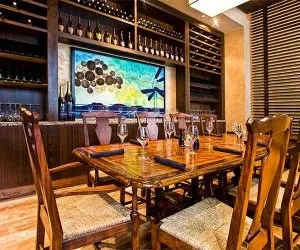 Sophisticated dining room features an ornate table, wine display, and abstract art.