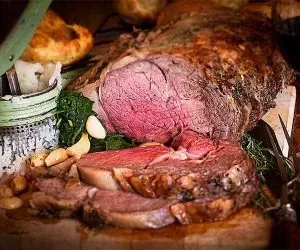 Partially carved medium-rare roast beef with garlic and herbs.