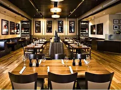 Empty upscale restaurant interior with warm lighting and modern dark wood decor.