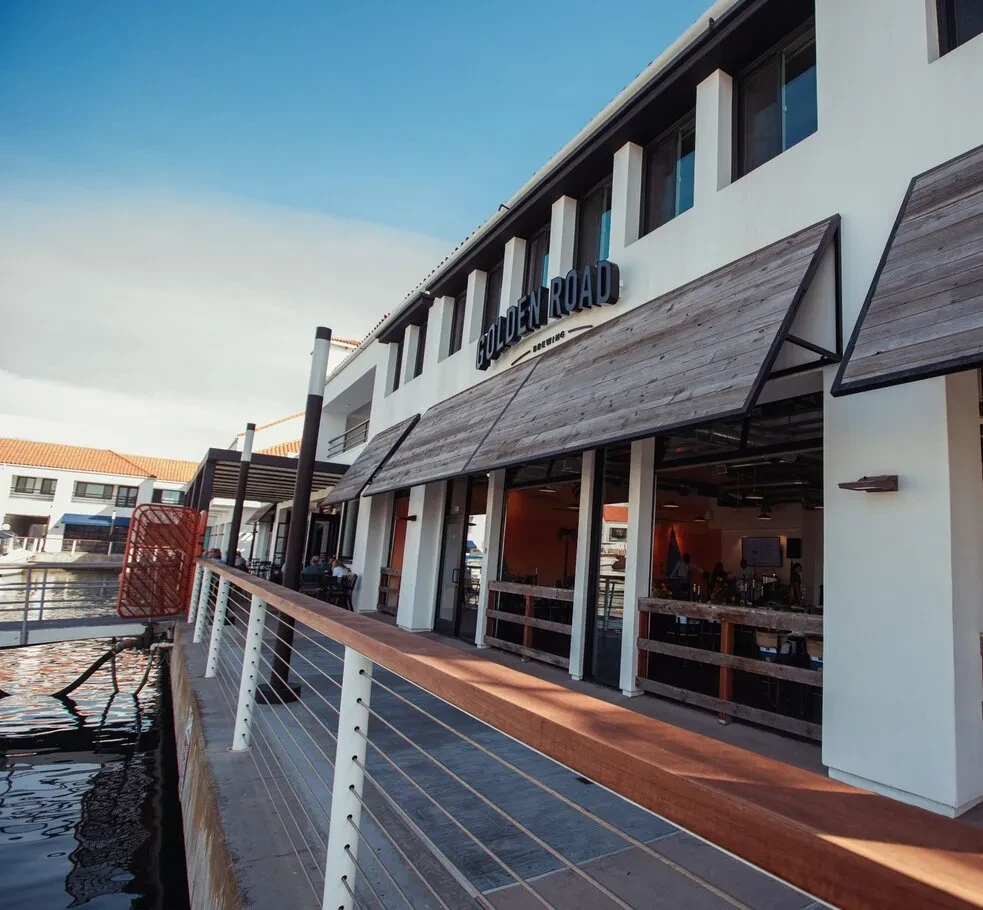 Waterfront Golden Road Brewing building with outdoor dining on a sunny day.