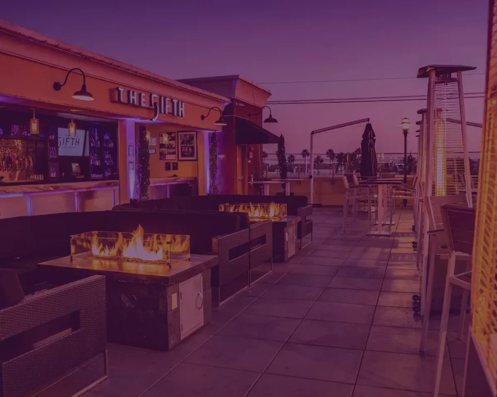 Purple-hued rooftop bar 'THE FIFTH' with lounge seating and fire pits.
