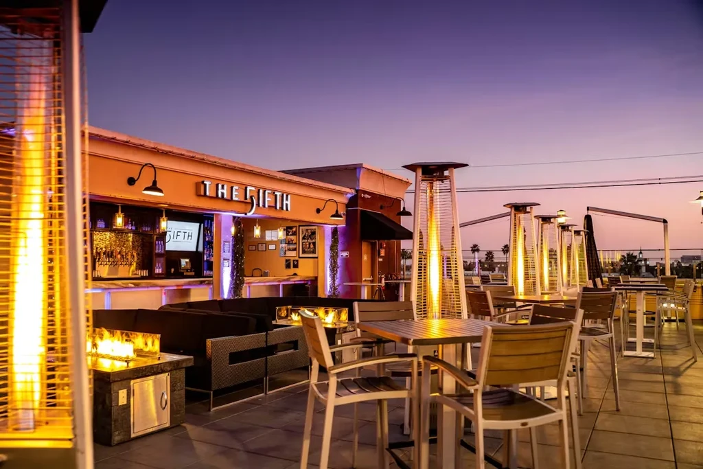 'THE 5IFTH' rooftop bar patio at dusk, with glowing heaters and fires.