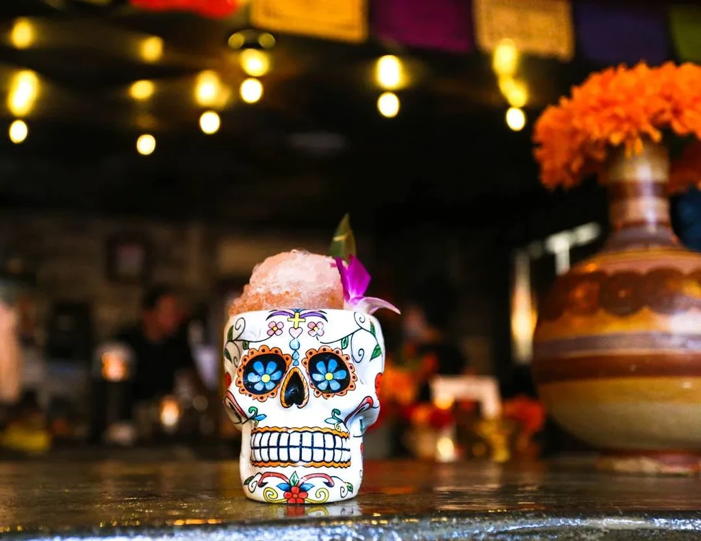 White folk art skull glass filled with a garnished cocktail.