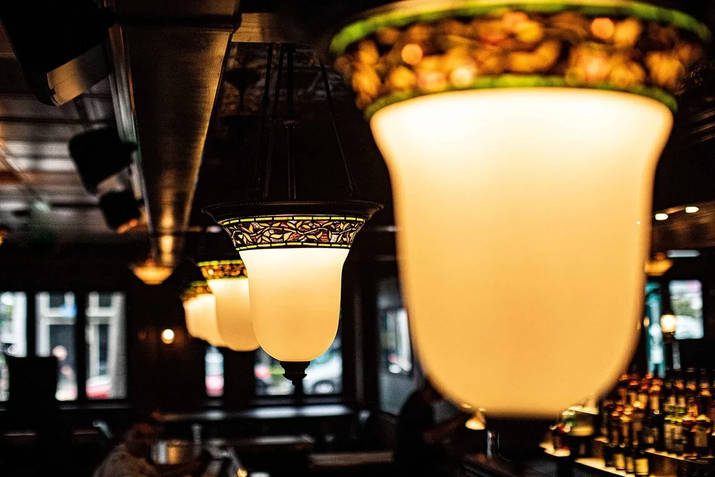 Ornate hanging light fixtures glow warmly in a dim bar interior.
