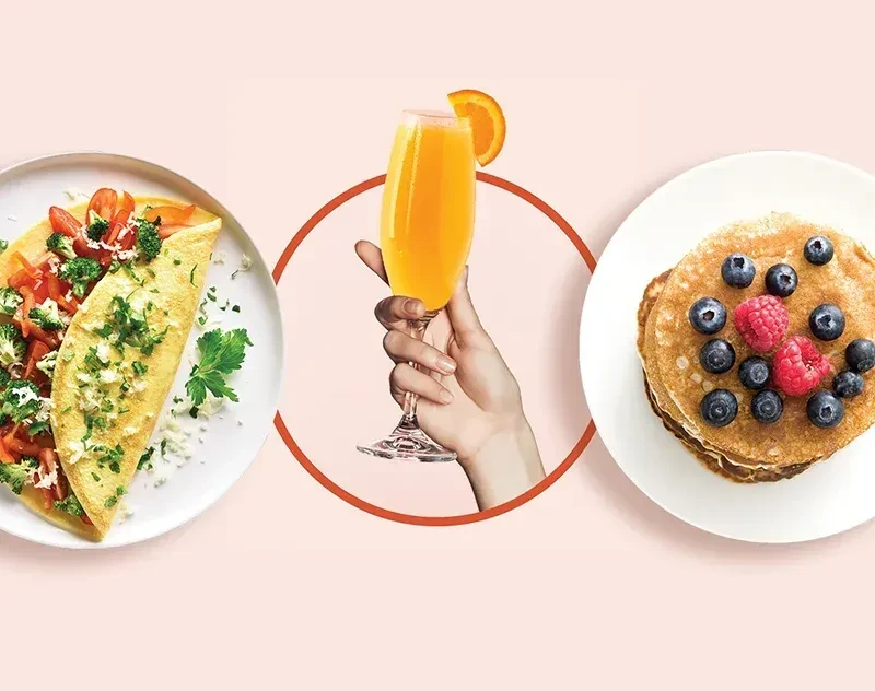 Breakfast omelet, orange mimosa, and berry pancakes on pink.