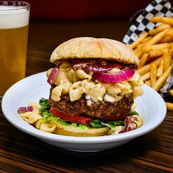 Gourmet burger topped with mac and cheese, beer, and fries.