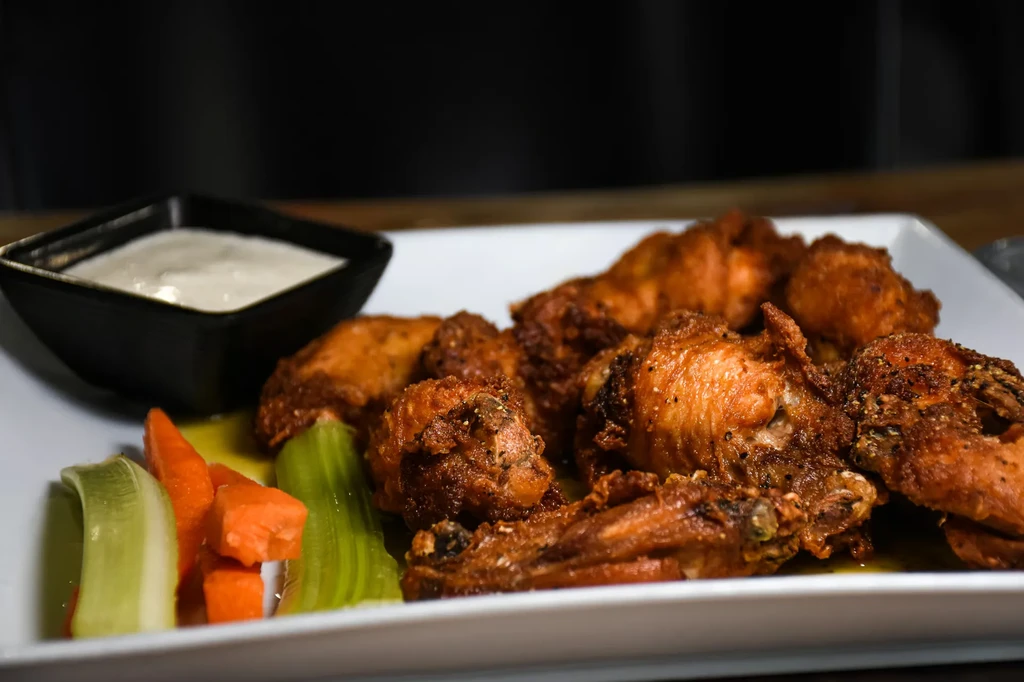 Crispy chicken wings, dipping sauce, carrot, and celery sticks.