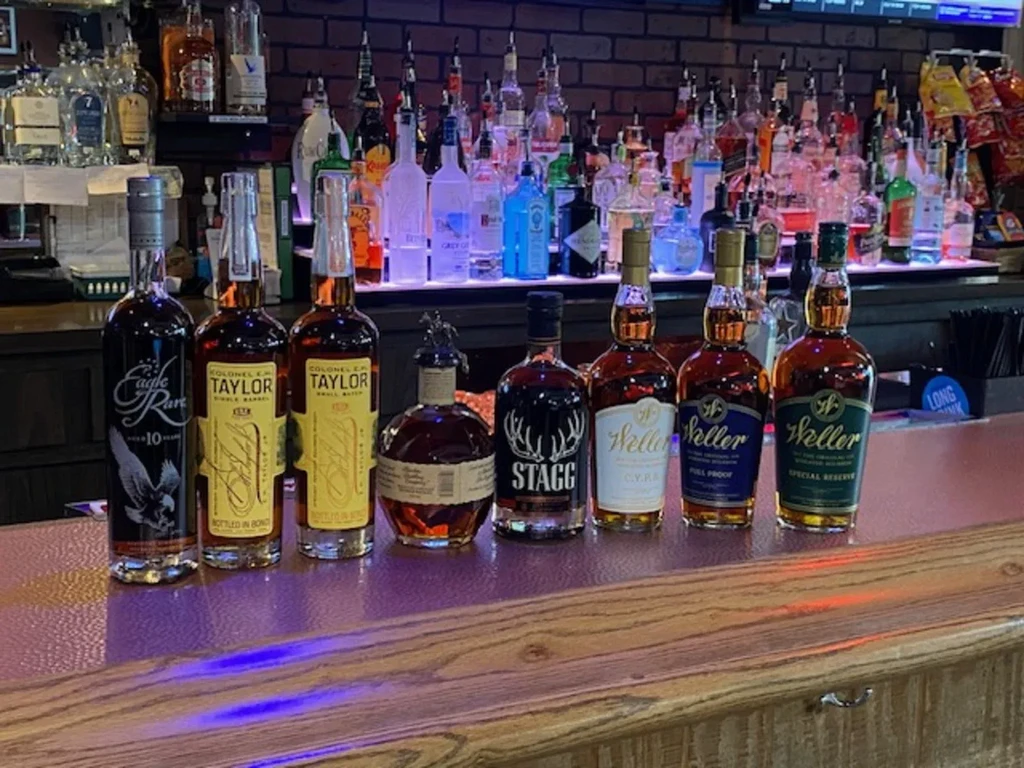 Premium whiskey and bourbon bottles displayed on a well-stocked bar.