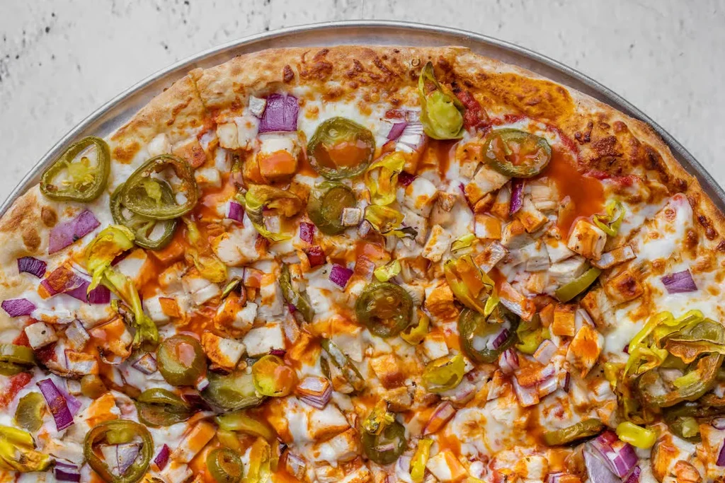 Freshly baked chicken pizza with jalapeños, onions, and buffalo sauce.