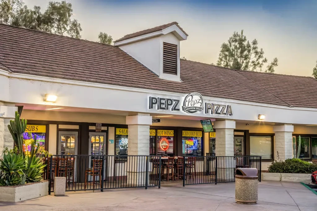 PEPZ Pizza storefront, with illuminated sign, neon menu, and patio.