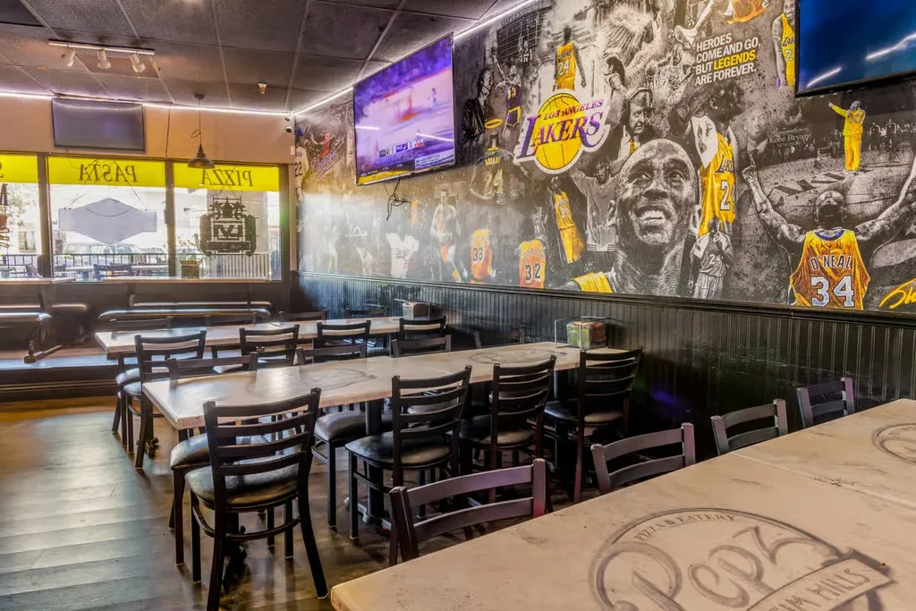 Empty sports bar dining room with a large Lakers mural and TVs.