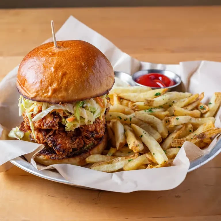 Close-up of crispy fried chicken sandwich, golden fries, and ketchup.