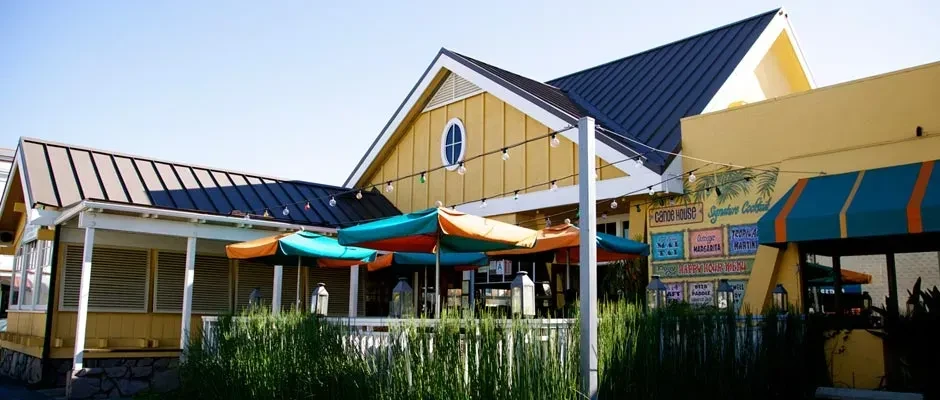 Bright yellow "Canoe House" restaurant with colorful outdoor patio umbrellas.