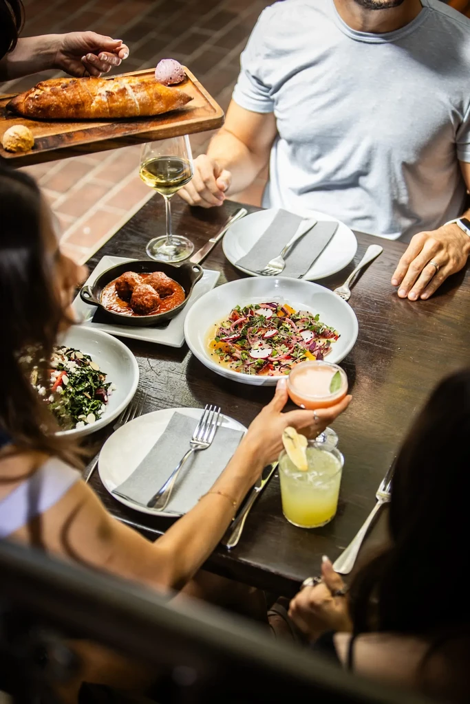 Overhead view of a restaurant table with various dishes, drinks, and diners.