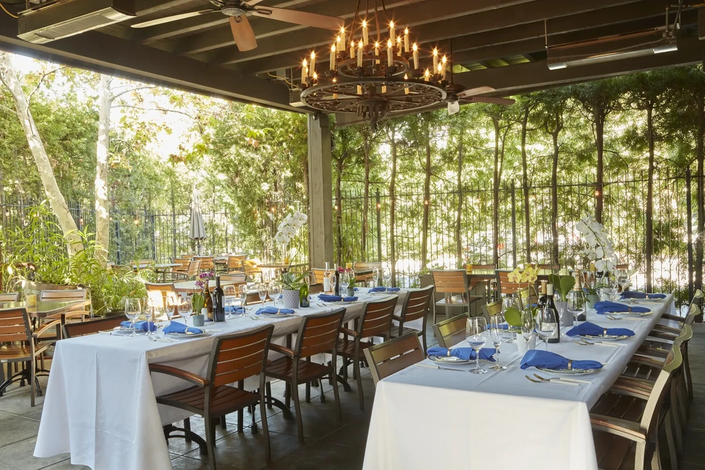 Outdoor restaurant patio with elegantly set tables, orchids, and a large chandelier.