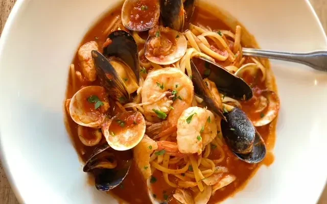 Top-down view of seafood linguine with shrimp, mussels, clams, and herbs.