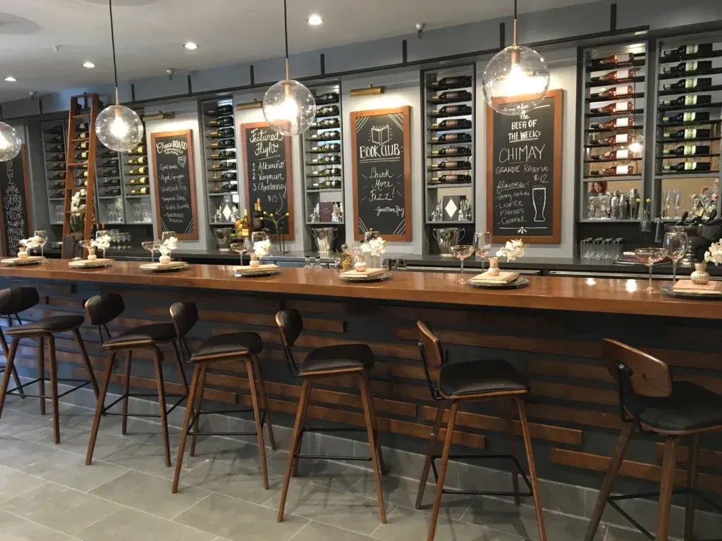 Well-lit modern bar with wine racks and menu displayed on chalkboards.