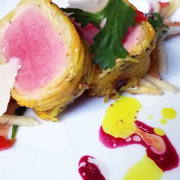 Plated dish: crispy pink meat, colorful sauces, and fresh garnishes.