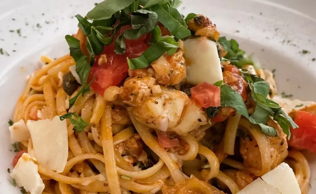 Linguine pasta with seafood, tomatoes, capers, cheese, and fresh basil.