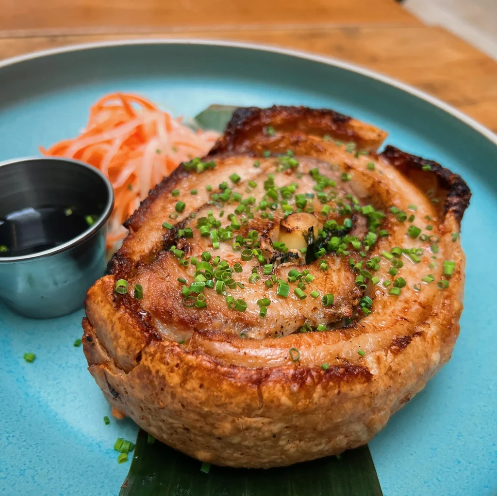 Golden-brown crispy pork belly roll, chives, sauce, and pickled daikon.