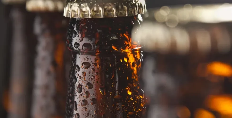 Amber glass bottle neck and metallic cap, covered in condensation.